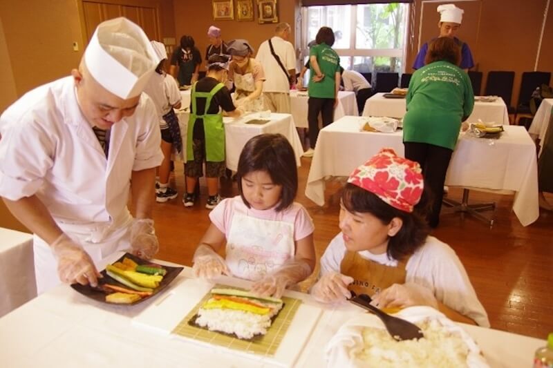 ひとり親家庭への支援の一環として「親子でお寿司作り体験教室」を開催。お寿司を巻く作業が楽しいと好評の声が。