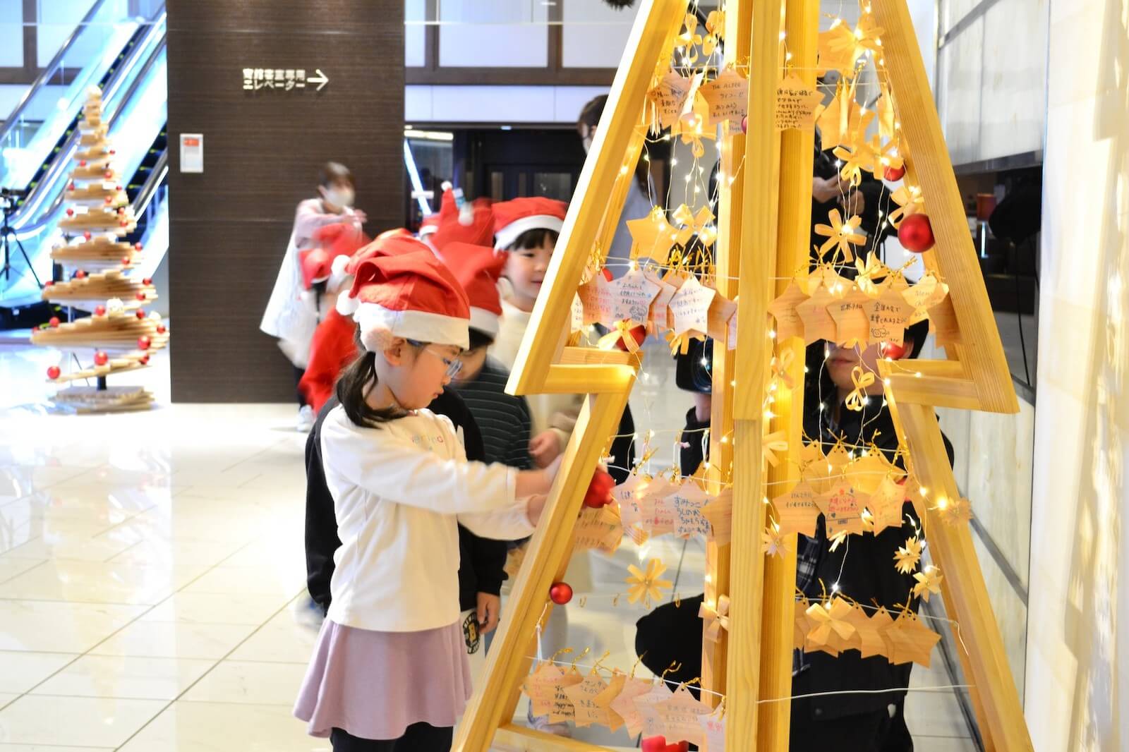 秋田杉の廃材で作られたクリスマスツリーに、子どもたちが飾り付けをする様子。誰でも参加できる地域参加型イベント『みんなでつくるクリスマスツリー』の場面。