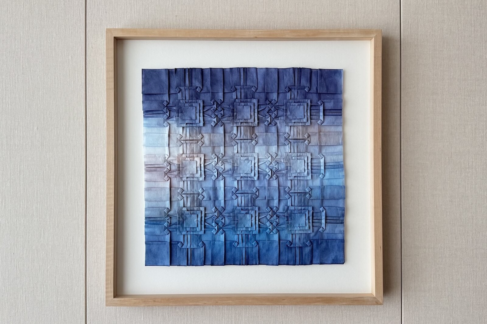 布施知子による折りの造形作品。青の濃淡で構成された幾何学的な構図が、ホテル館内の壁面に展示されている。