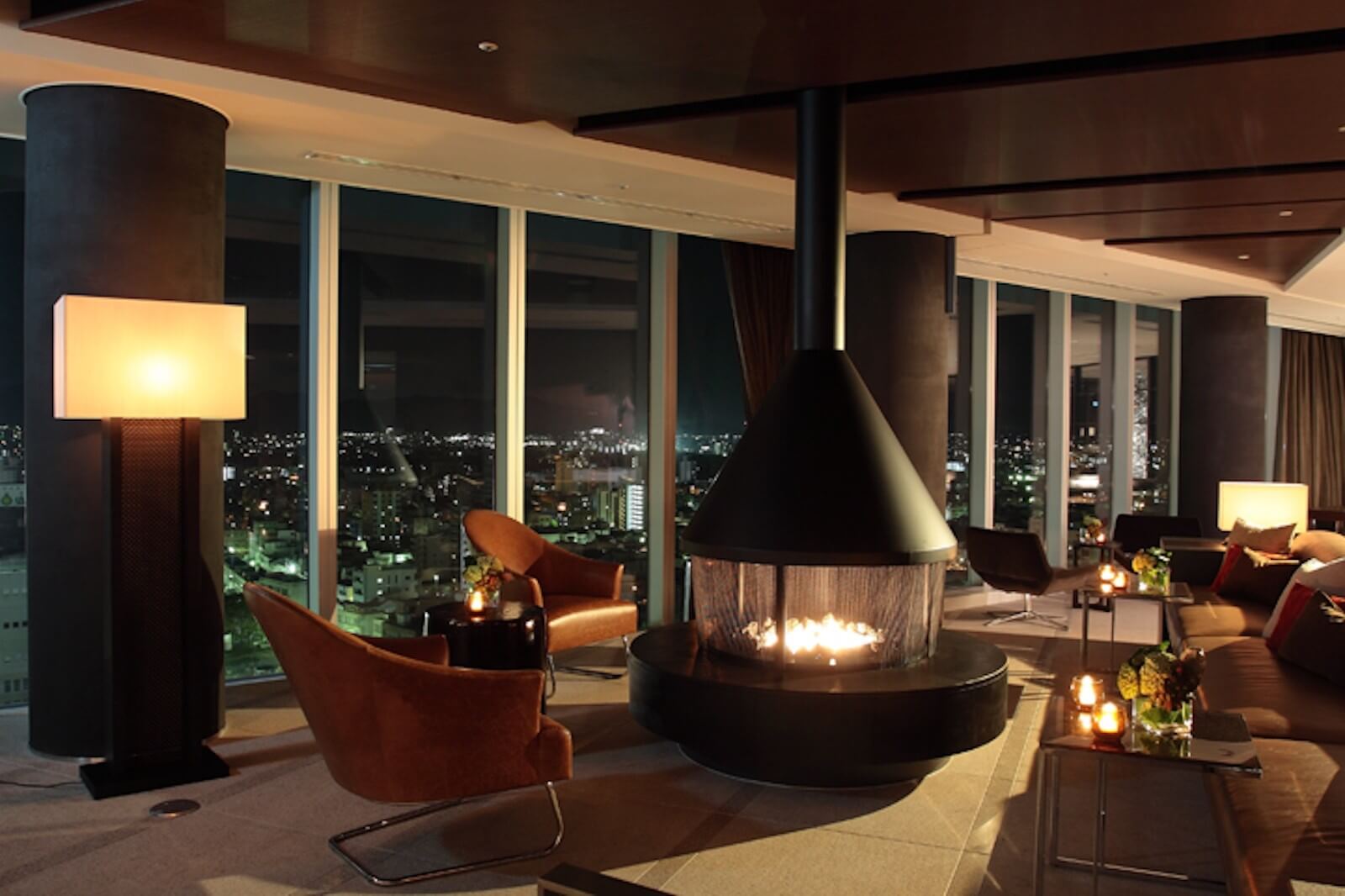 夜景を望む高層階ラウンジで、中央に暖炉を配し、ゆったりとしたソファやチェアが並ぶホテルアークリッシュ豊橋のくつろぎの空間