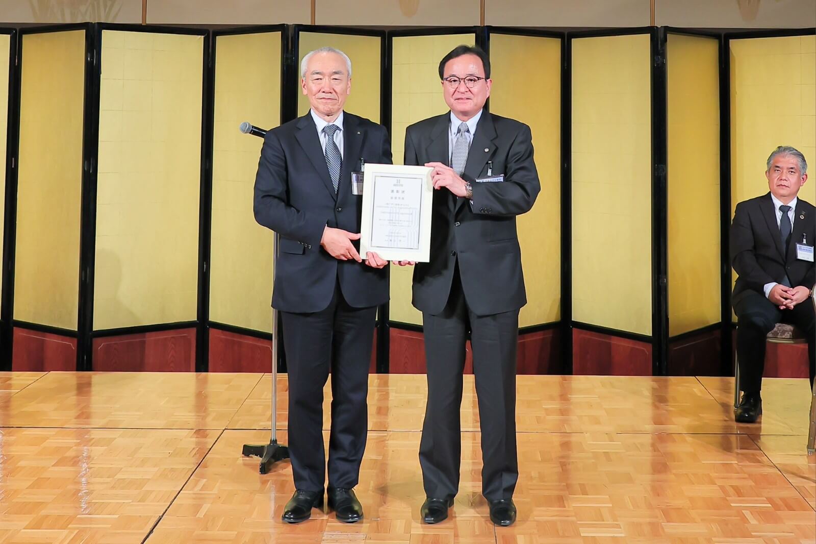 最優秀賞の表彰状を手にするSHIROYAMA HOTEL kagoshima代表者の矢野隆一社長(右)と䕃山会長。