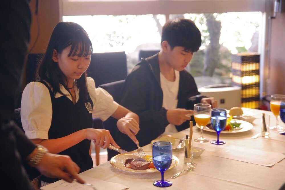 レストランで、ナイフとフォークを使って料理を食べるマナーを実践する子どもたちの様子。