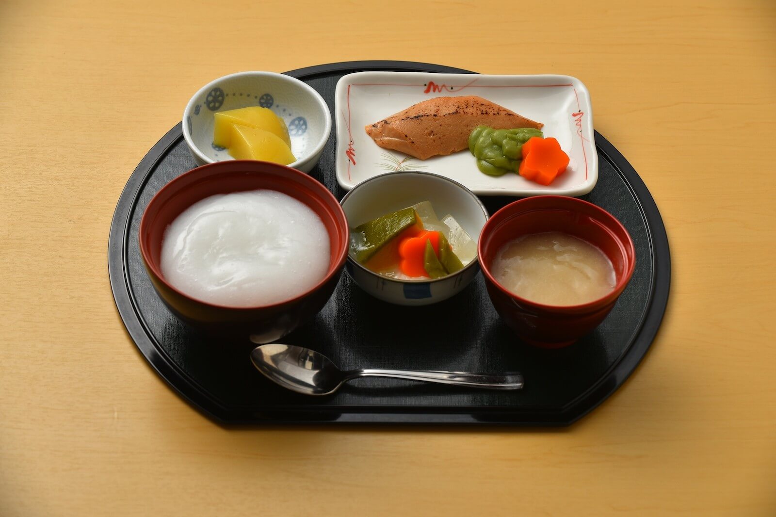 おかゆ、焼き魚、煮物、味噌汁がセットになった和食のトレー。