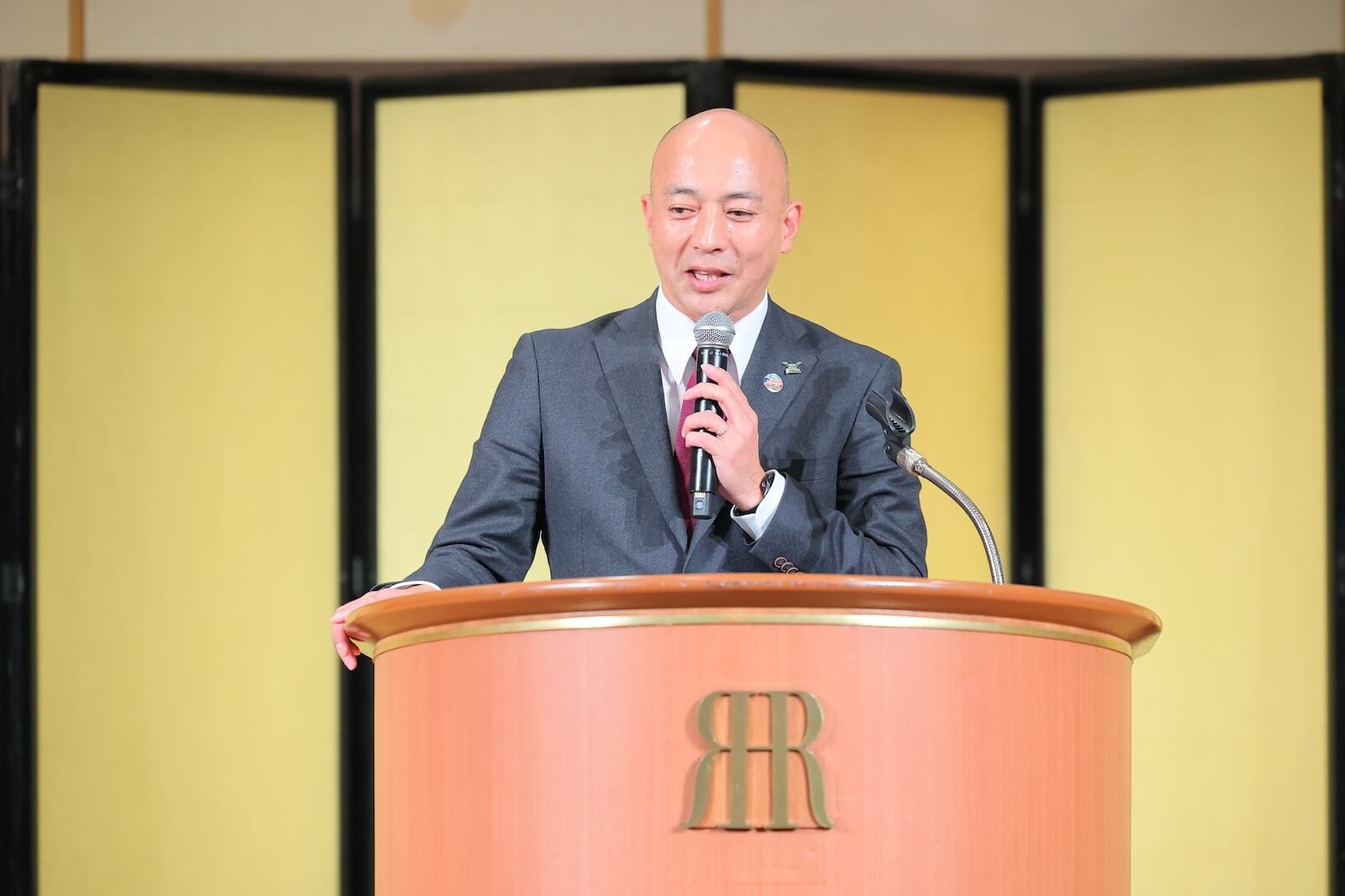演壇でマイクを手に講演する佐藤氏