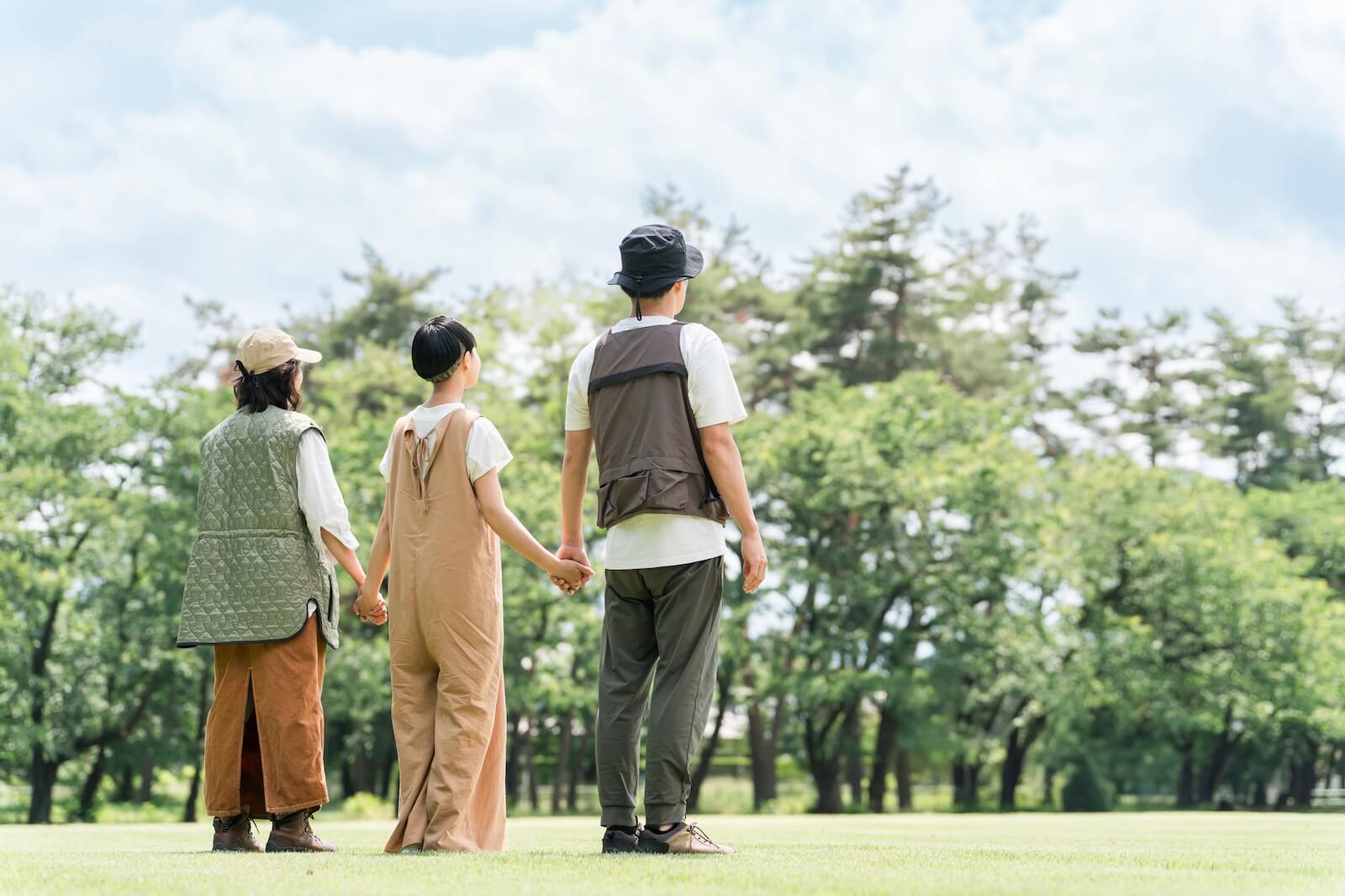 公園を歩く親子3人の後ろ姿