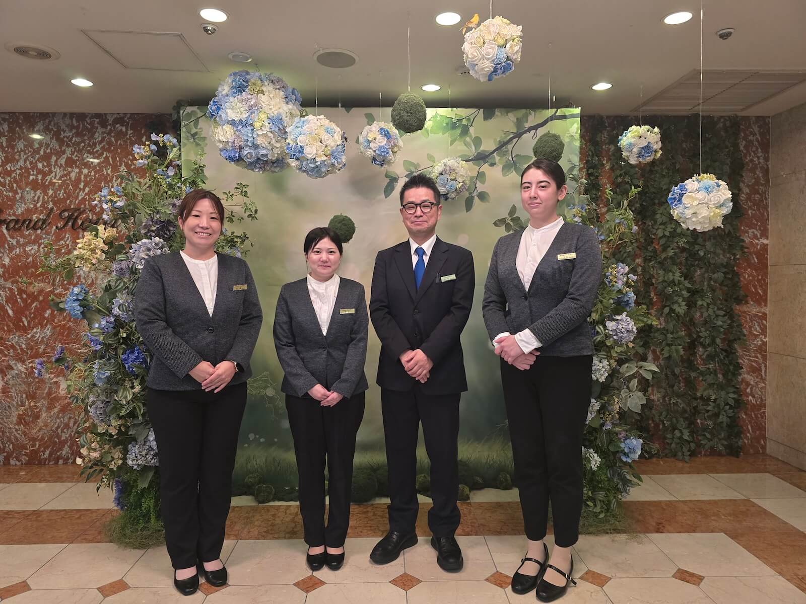 ホテルの装花を背景に並ぶ4人のスタッフ。